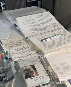 an open book sitting on top of a desk next to a cup and computer keyboard