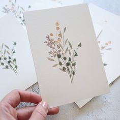 a hand is holding up some cards with flowers on the front and back of them