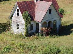 an old run down house with ivy growing on it's roof in a field