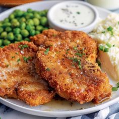 fried chicken and mashed potatoes on a white plate with peas, peas, and ranch dressing