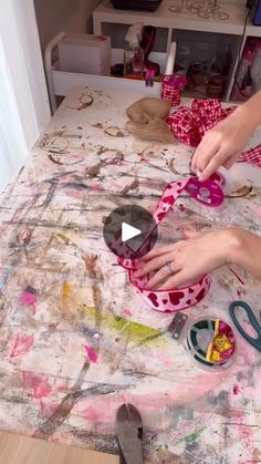 someone is painting on a table with scissors and other crafting supplies in the background