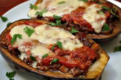 two stuffed eggplant boats on a white plate with parsley sprigs