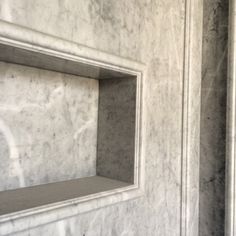 an empty niche in the side of a white marble wall with no one around it