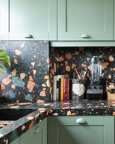 a kitchen with green cabinets and marble counter tops