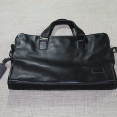 New! Black Leather Slim Brief Laptop Bag By Tumi. Never Used. Tags Still Attached. Style 063000d. The Interior Is Blue Fabric. There Are Three Bag Openings - Two Have Zipper Closures And The Center Is Open Without A Closure For Easy Access. The Side For The Laptop Is Quilted And Has A 10" X 8" Interior Pocket. The Center Opening Has A 4.5" X 6" Interior Side Pocket. The Other Zipper Closure Opening Has An Interior Zipper Pocket, An Open Interior Pocket And Two Pen/Pencil Holders And Two Card Hol Black Leather-lined Briefcase For Everyday, Tumi Briefcase, Black Leather-trimmed Laptop Bag For Travel, Versatile Black Laptop Bag With Anti-theft Pocket, Black Briefcase With Removable Pouch For On-the-go, Tumi Bags, Blue Fabric, Laptop Bag, Zipper Pocket