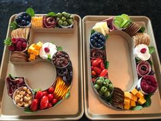 two trays filled with fruit and crackers shaped like the number 50 on top of each other