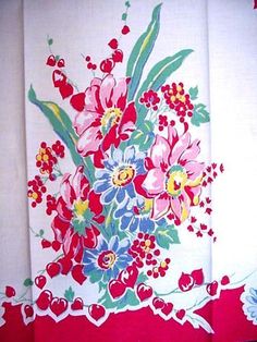 a red and white table cloth with colorful flowers on it, in front of a wall