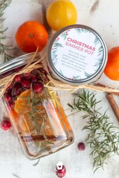 a jar filled with oranges and rosemary next to some lemons on a table