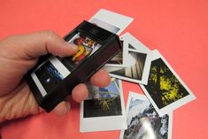 a hand holding an old fashioned camera over several polaroid photos on a pink surface