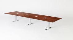 a long wooden table sitting on top of a white floor next to two metal legs