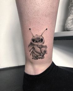 a black and white photo of a small insect tattoo on the right leg, with two smaller bugs in it's legs