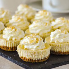 coconut cream cheesecake cupcakes are sitting on a black tray with white frosting