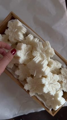 a person is holding something in a box with white flowers on the inside and outside