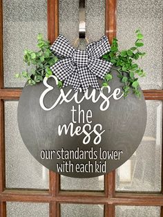 a metal sign that says, exuse the mess our standards lower with each kid