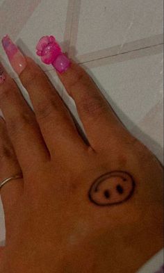 a woman's hand with pink nail polish and smiley face on her left wrist