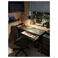 a desk with a laptop and other items on it, in front of a window