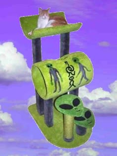 a cat sitting on top of a green scratching post with an alien theme and sky in the background