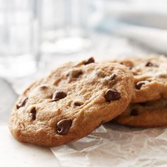 two chocolate chip cookies sitting on top of paper