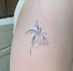 a small tattoo on the back of a woman's left thigh, with a blue and green flower