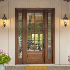 the front door is open and there are flowers in vases on the porch next to it