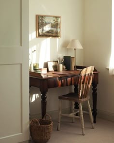 a room with a desk, chair and lamp on it in front of a window