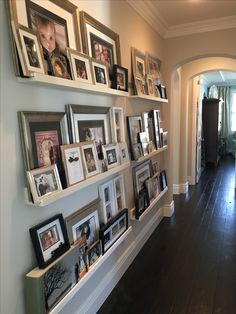 a long hallway with many pictures on the wall and framed photos on the shelves above it