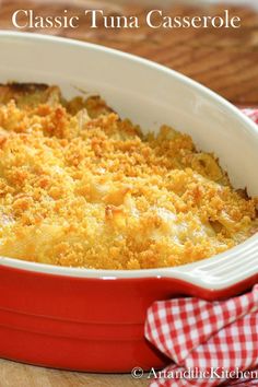 a red casserole dish filled with macaroni and cheese on a wooden table