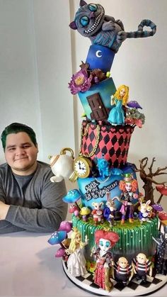 a man sitting in front of a large cake with many figurines on it