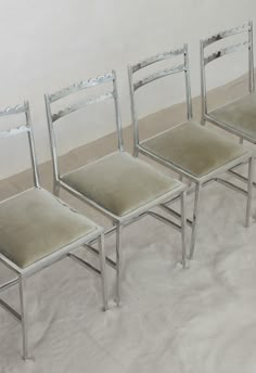 three silver chairs sitting next to each other on top of a white carpeted floor