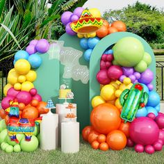 a birthday party with balloons and decorations on the grass in front of a sign that says happy birthday