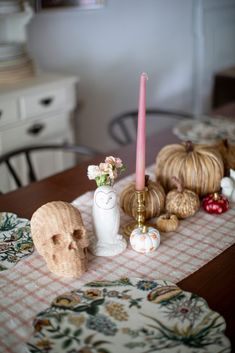 a table topped with a vase filled with flowers next to a candle and other items