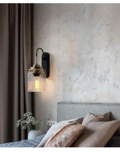 a bed sitting under a wall light next to a window