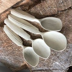 five spoons are sitting on top of a piece of wood