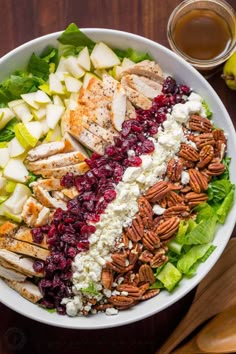 a salad with chicken, cranberry sauce and pecans in it on a wooden table