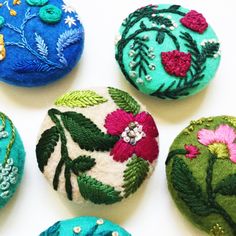 four different colored buttons with flowers and leaves on them, all made out of felt