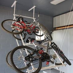 there is a bike hanging from the ceiling in this garage with two bikes on it