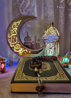 an open book sitting on top of a table next to a lamp and lantern holder