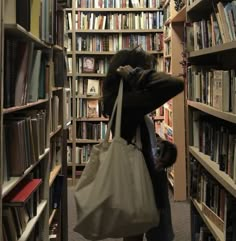 a woman is standing in front of a bookshelf with a bag on her shoulder