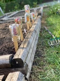 some logs are lined up on the ground in front of grass and dirt, with small plastic bottles attached to them