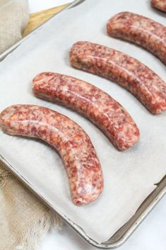 four sausages on a baking sheet ready to be cooked in the oven for dinner