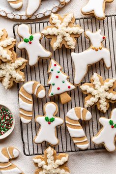 decorated cookies on a cooling rack next to a bowl of sprinkles and sugar