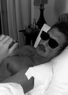 a man laying in bed with sunglasses on his face