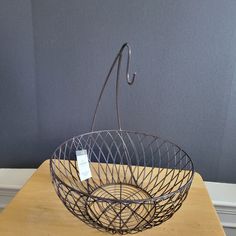 a wire basket on a table with a price tag hanging from the handle and hook