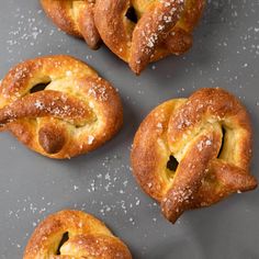 four pastries with powdered sugar on them sitting on a gray surface next to each other