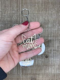 a hand holding a glass keychain with the word cat mom written on it