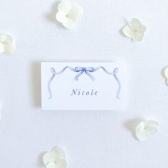 a card with the name nicole on it surrounded by small white flowers and tiny petals