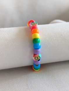 a colorful bracelet is sitting on top of a white napkin with a teddy bear bead in it