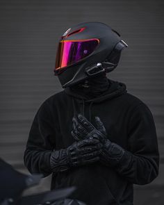 a person wearing a helmet and gloves standing next to a motorcycle