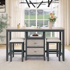 a kitchen table with two stools and a vase on it in front of a window