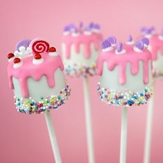 cake pops with pink icing and sprinkles on them, sitting in front of a pink background